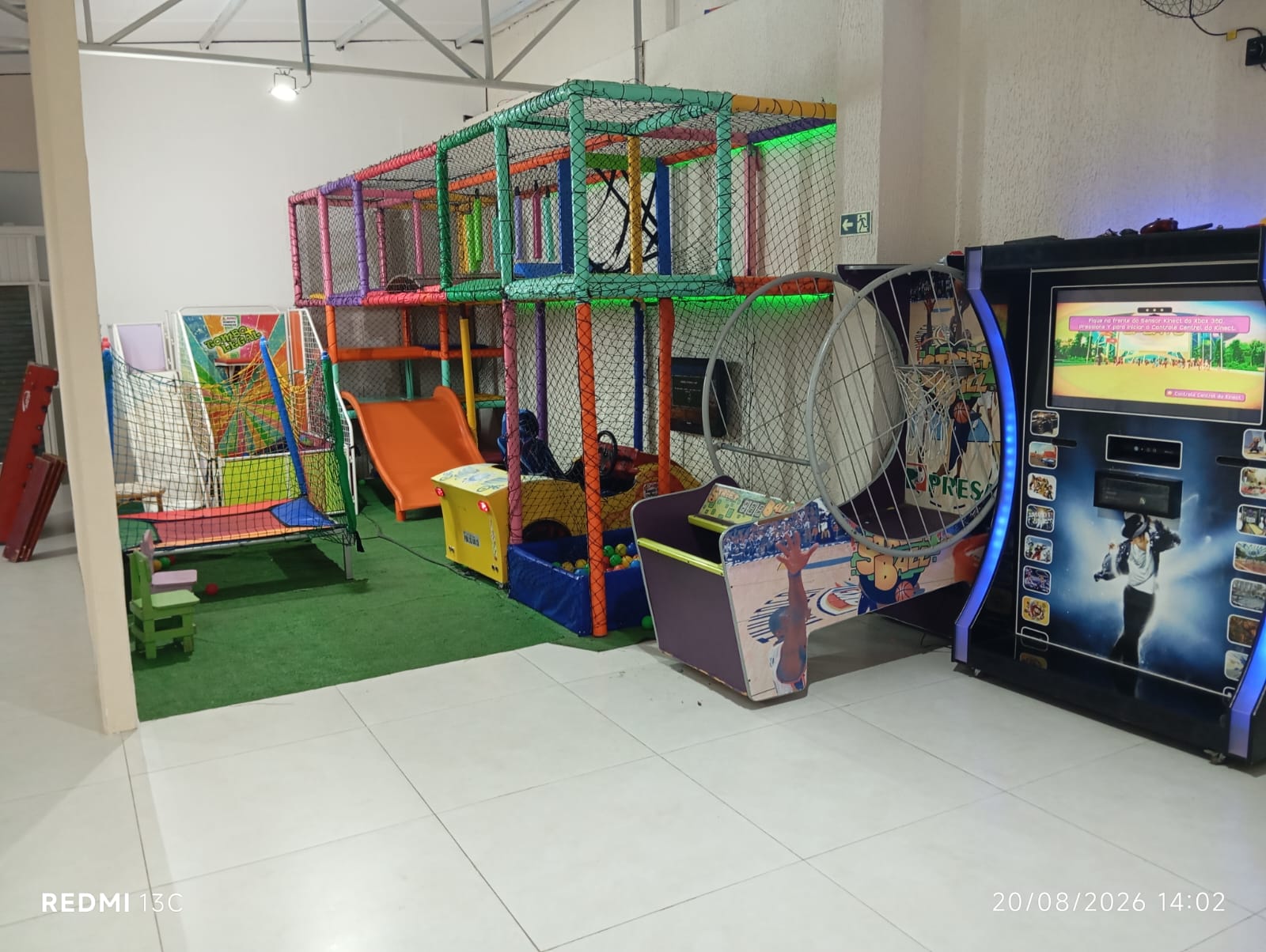 Espaço interno da casa de festas com brinquedos, cama elástica e jogos eletrônicos